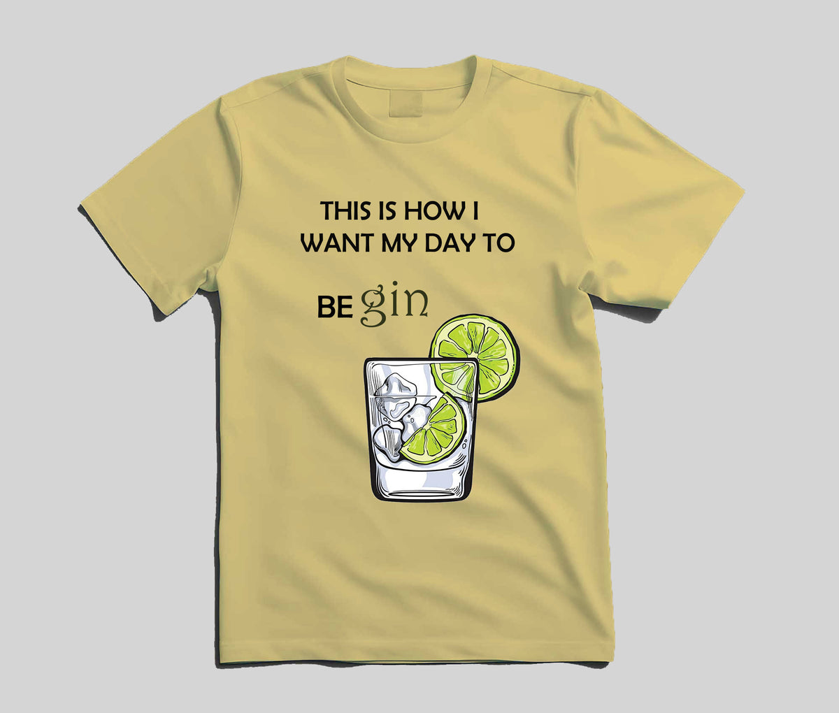 A pale yellow short-sleeve t-shirt with a graphic print that reads 'THIS IS HOW I WANT MY DAY TO BE gin' above an illustration of a highball glass with ice, a lime slice, and a lime wheel, shown on a neutral gray background.