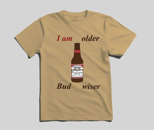 A beige short-sleeve t-shirt with a graphic print of a Budweiser bottle and the text 'I am older Bud wiser' in red and black, displayed on a neutral gray background.