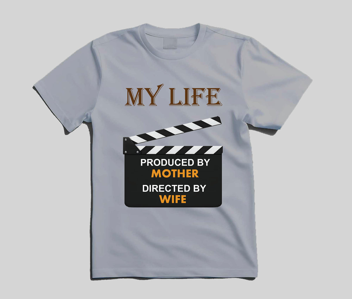 A light blue short-sleeve t-shirt with a graphic print featuring a clapperboard and the text 'MY LIFE PRODUCED BY MOTHER DIRECTED BY WIFE' in brown, black, and orange, displayed on a neutral gray background.